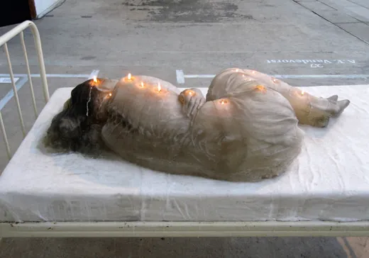 A.F. Vandevorst “Dreaming”, Arnhem Mode Biennale 2011: life-size candle-wax sculpture of a sleeping girl on a hospital bed, wicks lit