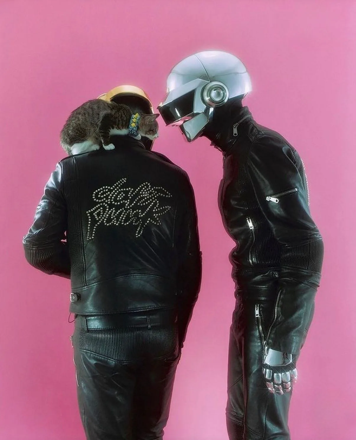 Daft Punk in Dior Homme leather on a pink backdrop, a cat on one shoulder