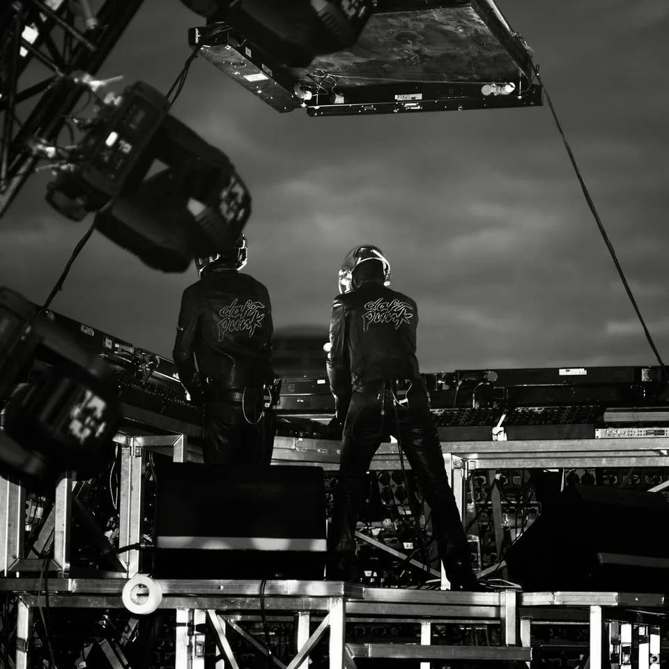 Daft Punk on stage from behind, the studded logo on their jackets