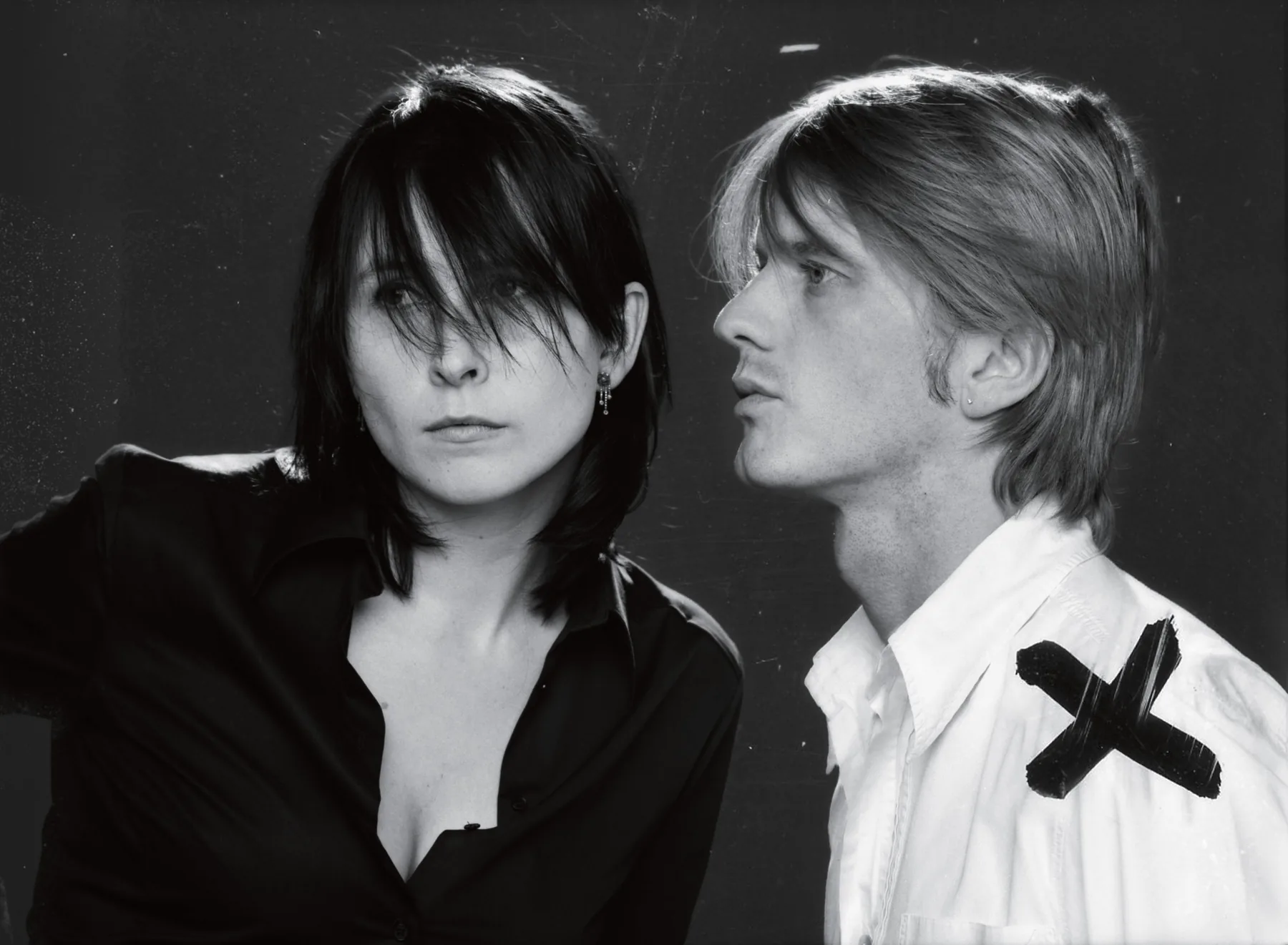 An Vandevorst and Filip Arickx, black-and-white portrait: she in a black shirt, he in a white shirt marked with a black cross