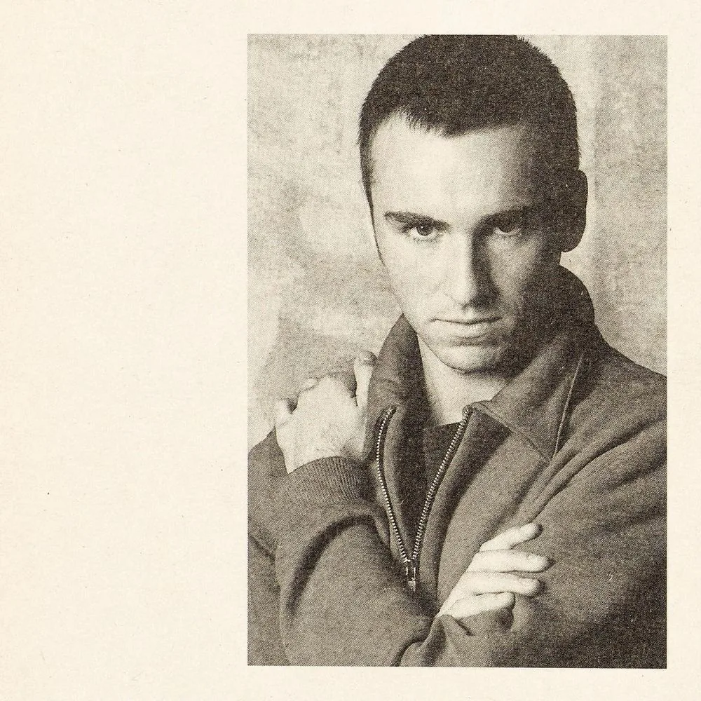 Raf Simons in the 1990s, arms crossed in a zip-up jacket, magazine page
