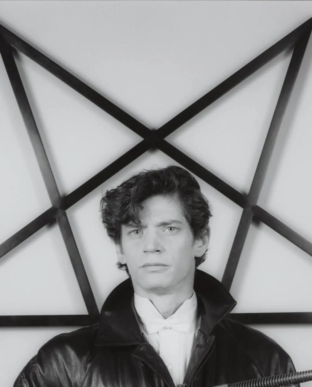Robert Mapplethorpe in a leather jacket in front of a large five-pointed star, black-and-white