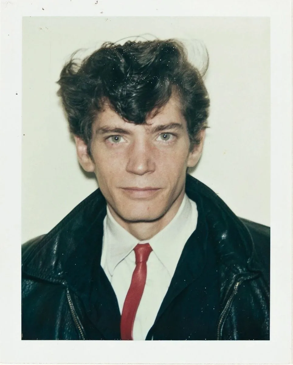 Robert Mapplethorpe in a leather jacket and red tie, colour Polaroid
