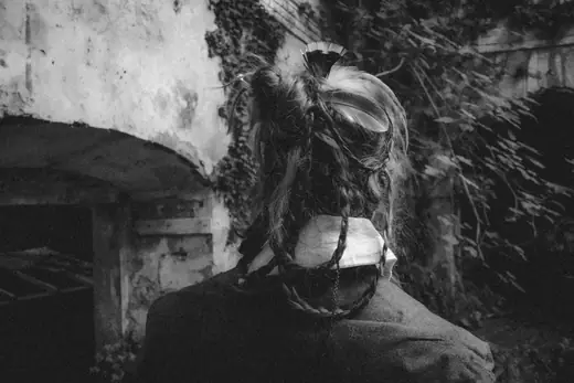 Post Mortem by Tommaso Curatella, look 1: back view of braided hair and a high white collar in a ruined building